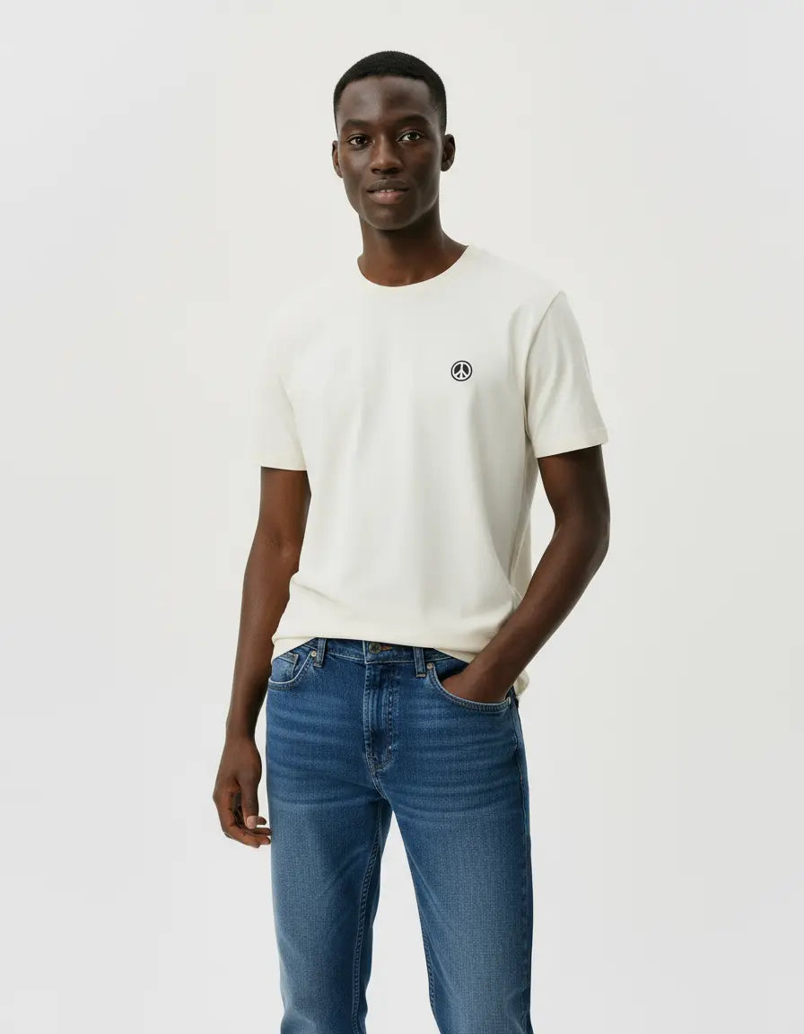 Man wearing a white t-shirt with a small peace sign patch